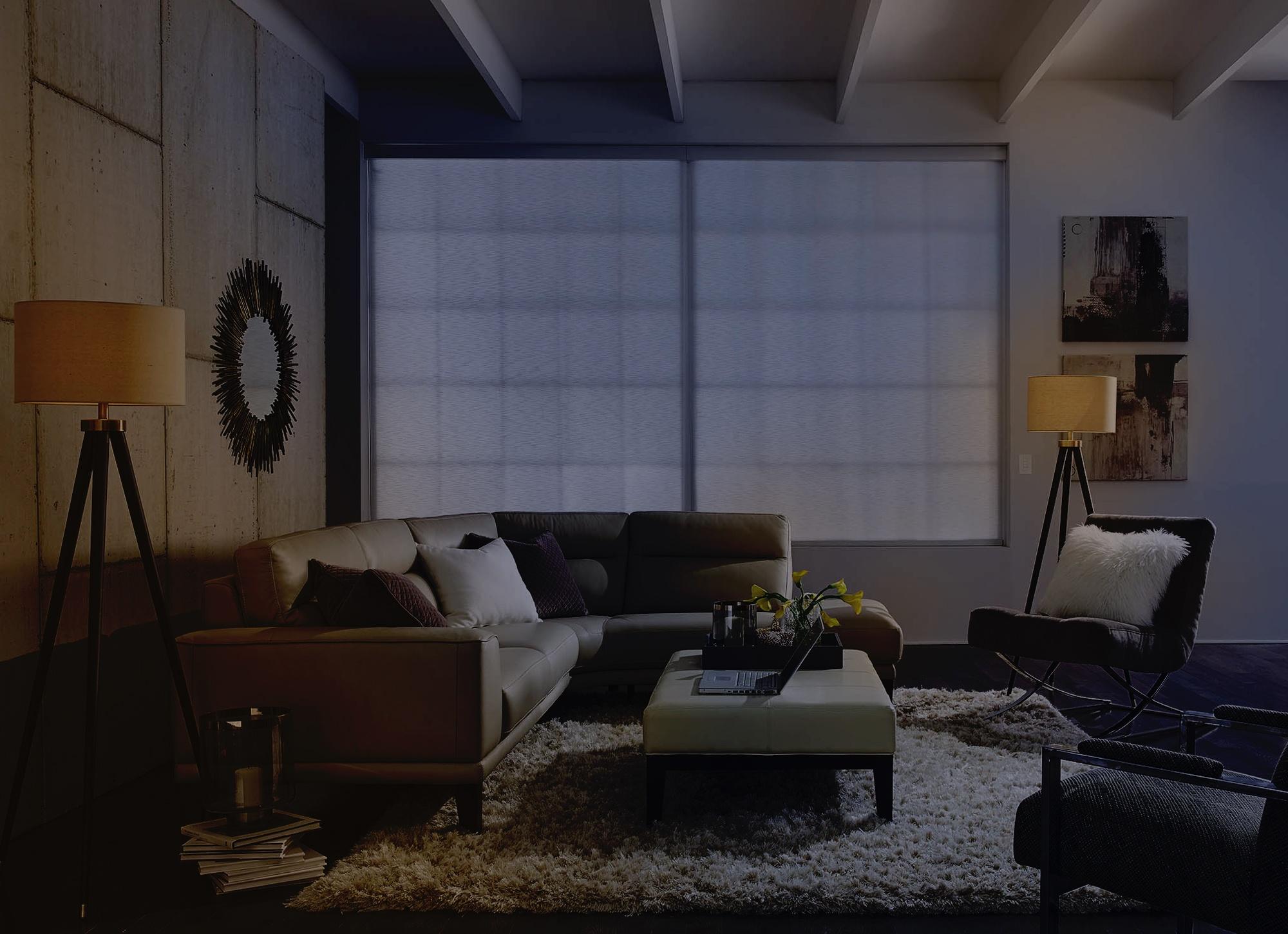 Cozy living room with dim lighting, showcasing a white sectional sofa, floor lamps, and a soft, inviting atmosphere.